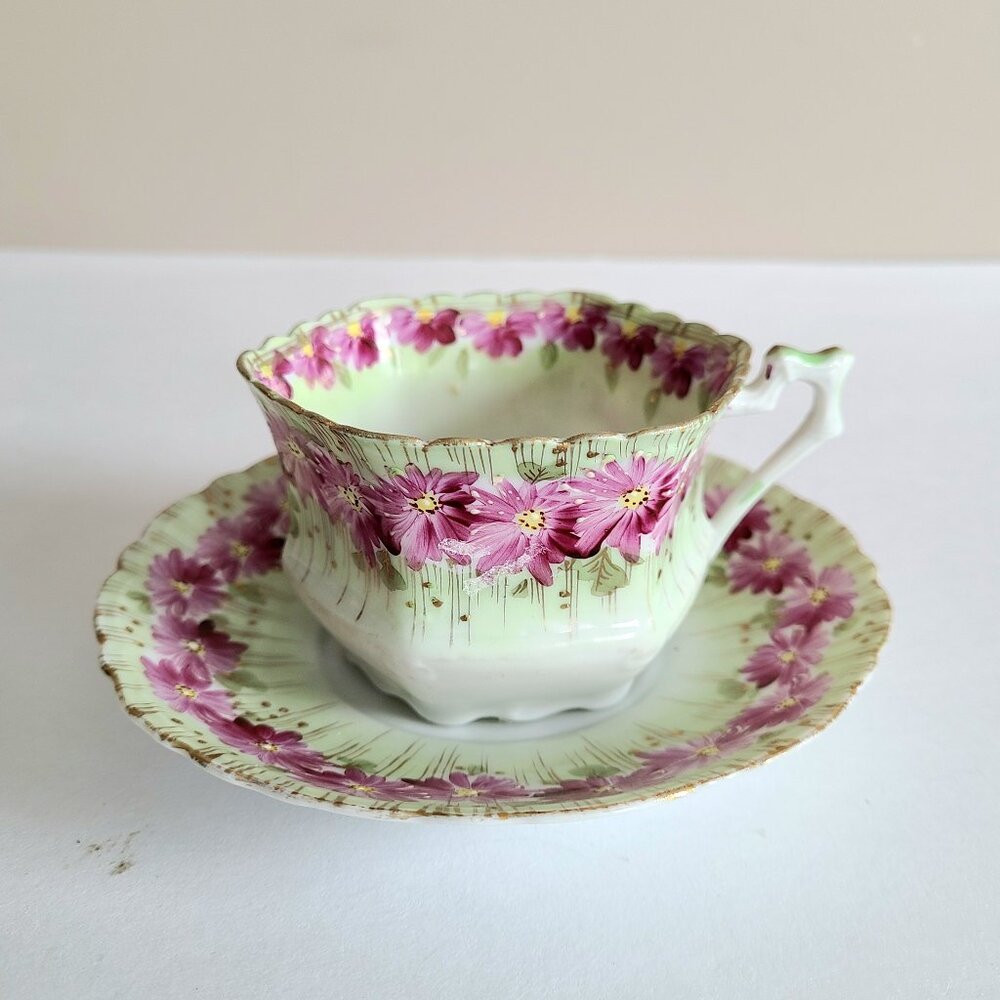 Antique porcelain tea cup with saucer with pink floral design and gold trim.